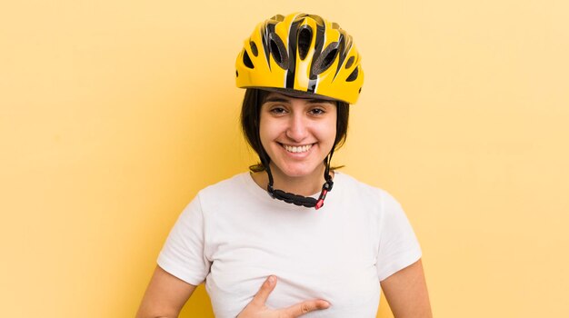 Giovane donna ispanica che ride ad alta voce per qualche esilarante concetto di casco da bici scherzo