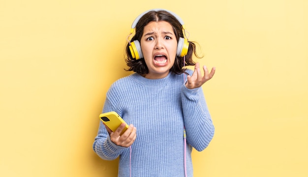 Giovane donna ispanica che sembra disperata, frustrata e stressata. cuffie e concetto di smartphone