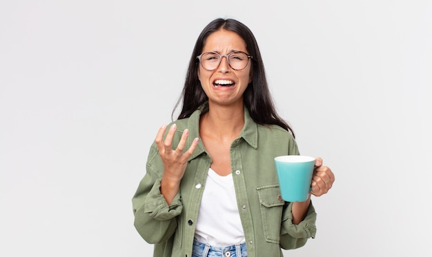 Giovane donna ispanica che sembra disperata, frustrata e stressata e tiene in mano una tazza da caffè