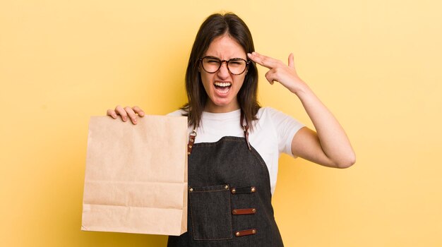 Giovane donna ispanica che sembra gesto di suicidio infelice e stressato facendo segno di pistola fast food consegnare il concetto