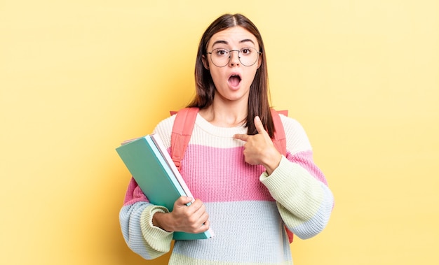 Giovane donna ispanica che sembra scioccata e sorpresa con la bocca spalancata, che indica se stessa. concetto di studente