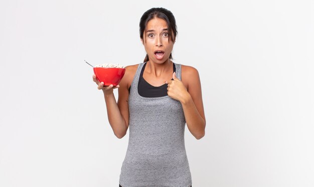 Giovane donna ispanica che sembra scioccata e sorpresa con la bocca spalancata, che indica se stessa. dieta fitness e concetto di colazione