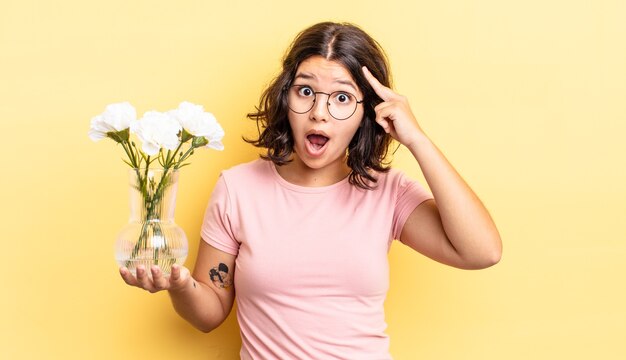 giovane donna ispanica che sembra sorpresa, realizzando un nuovo pensiero, idea o concetto. concetto di vaso di fiori