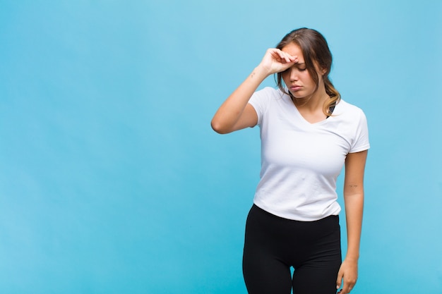 Giovane donna ispanica che sembra stressata, stanca e frustrata, asciugandosi il sudore dalla fronte, sentendosi senza speranza ed esausta