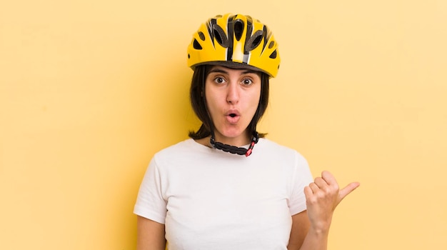 Giovane donna ispanica che sembra stupita nel concetto di casco da bici incredulo