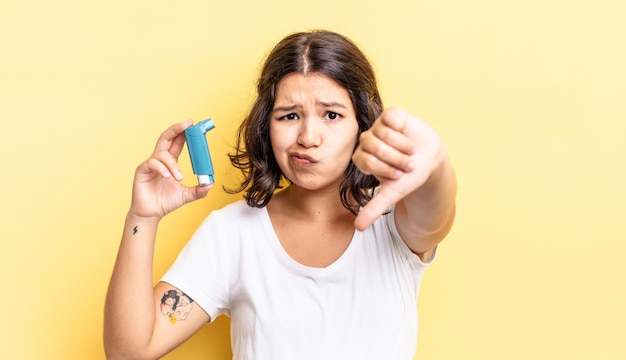 Giovane donna ispanica che si sente croce, mostra i pollici in giù. concetto di asma