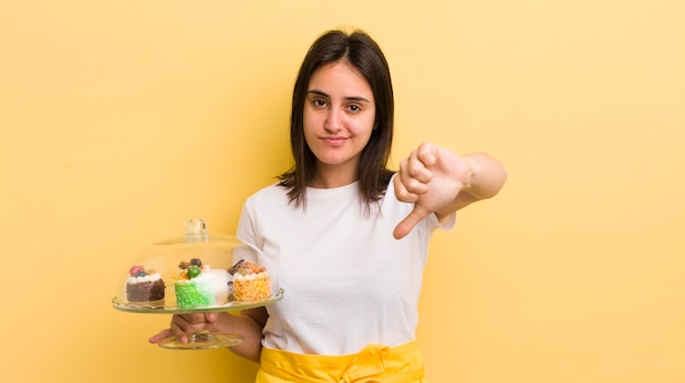 Giovane donna ispanica che si sente crossshowing pollice verso il concetto di torte fatte in casa