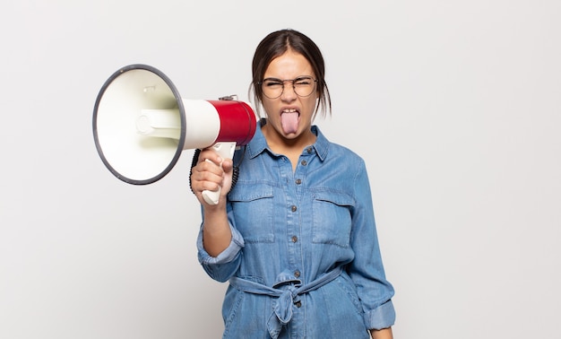 Giovane donna ispanica che si sente disgustata e irritata, sporge la lingua, non ama qualcosa di brutto e schifoso