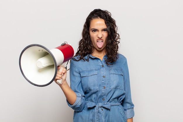 Giovane donna ispanica che si sente disgustata e irritata, sporge la lingua, non ama qualcosa di brutto e schifoso