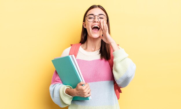 Giovane donna ispanica che si sente felice, dando un grande grido con le mani vicino alla bocca. concetto di studente