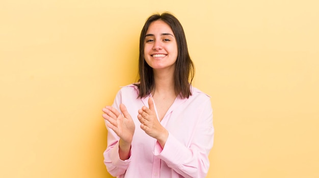 Giovane donna ispanica che si sente felice e di successo sorride e batte le mani dicendo congratulazioni con un applauso