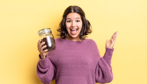 Giovane donna ispanica che si sente felice e stupita per qualcosa di incredibile. concetto di chicchi di caffè