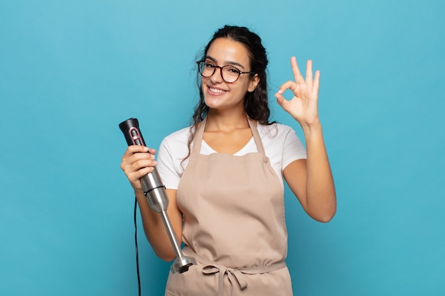 Giovane donna ispanica che si sente felice, rilassata e soddisfatta, mostrando approvazione con un gesto ok, sorridendo