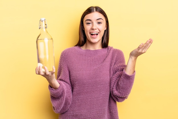Giovane donna ispanica che si sente felice, sorpresa nel realizzare una soluzione o un'idea. concetto di bottiglia d'acqua