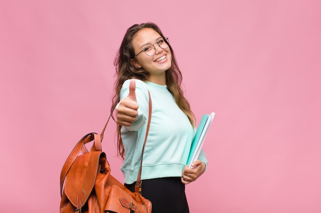 Giovane donna ispanica che si sente orgogliosa, spensierata, sicura e felice, sorridendo positivamente con i pollici in su