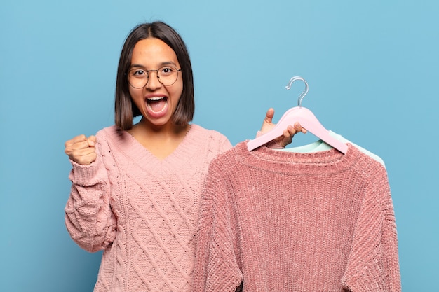 Giovane donna ispanica che si sente scioccata, eccitata e felice, ridendo e celebrando il successo