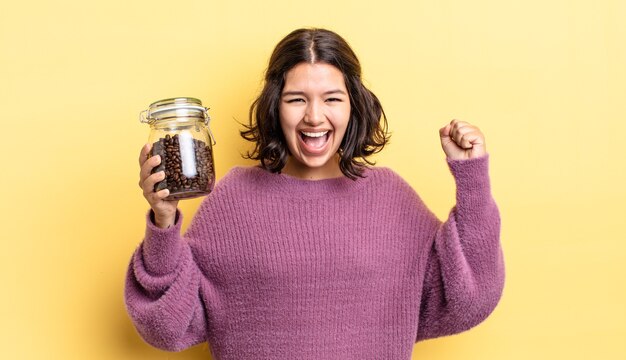 Giovane donna ispanica che si sente scioccata, ride e celebra il successo. concetto di chicchi di caffè