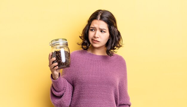 giovane donna ispanica che si sente triste, sconvolta o arrabbiata e guarda di lato. concetto di chicchi di caffè