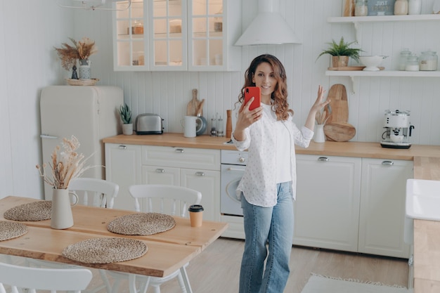 Giovane donna ispanica che si vanta con la sua cucina elegante La casalinga ha una videochiamata a casa