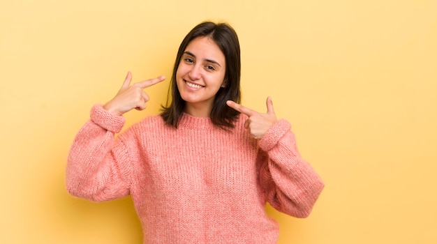 Giovane donna ispanica che sorride con sicurezza indicando il proprio ampio sorriso positivo rilassato atteggiamento soddisfatto