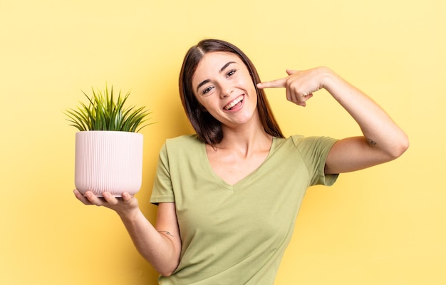 Giovane donna ispanica che sorride con sicurezza indicando il proprio concetto di vaso per piante ampio sorriso
