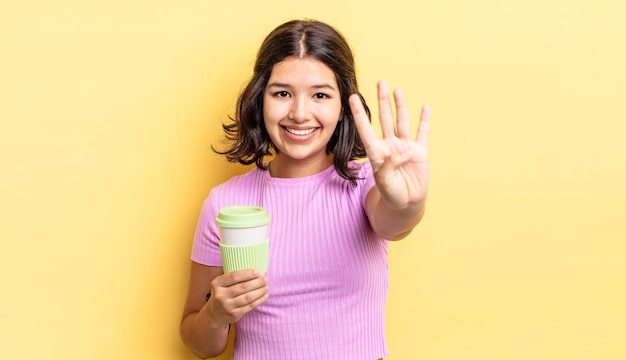 Giovane donna ispanica che sorride e che sembra amichevole, mostrando il numero quattro. portare via il concetto di caffè