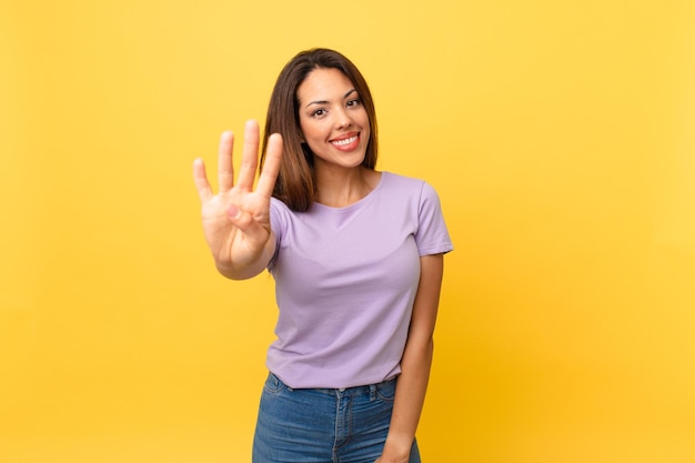 Giovane donna ispanica che sorride e sembra amichevole, mostrando il numero quattro