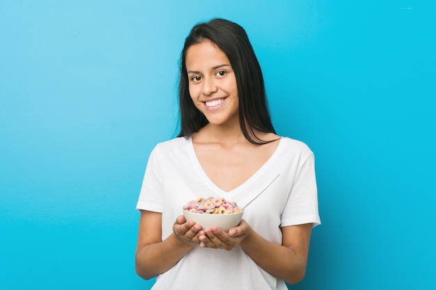 Giovane donna ispanica che tiene una ciotola di cereali di zucchero felice, sorridente e allegra