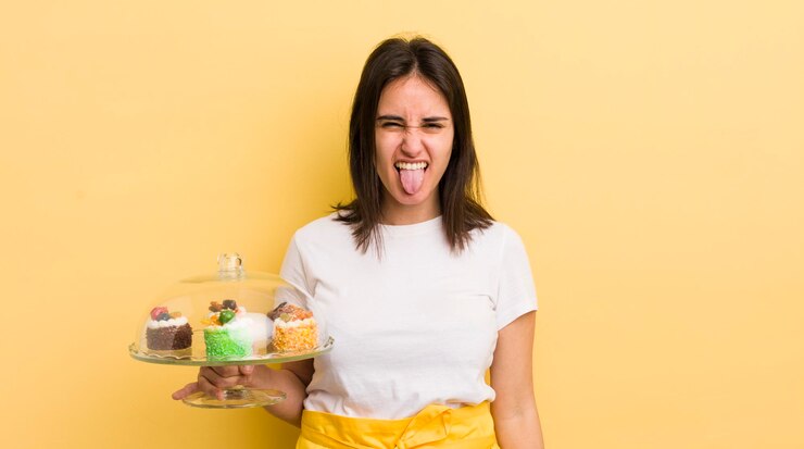 Giovane donna ispanica con atteggiamento allegro e ribelle che scherza e tira fuori la lingua concetto di torte fatte in casa