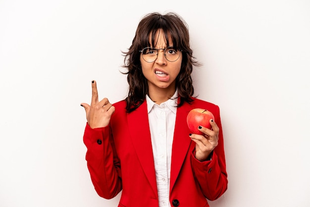 Giovane donna ispanica di affari che tiene una mela isolata su fondo bianco che mostra un gesto di delusione con l'indice