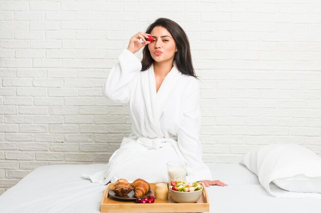 Giovane donna ispanica facendo colazione a letto