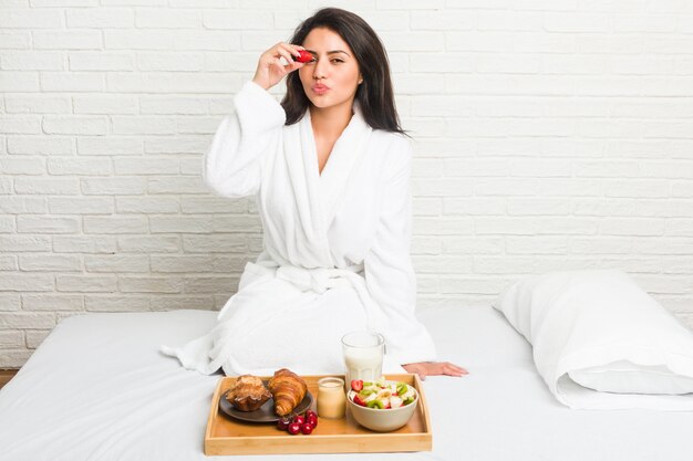 Giovane donna ispanica facendo colazione sul letto