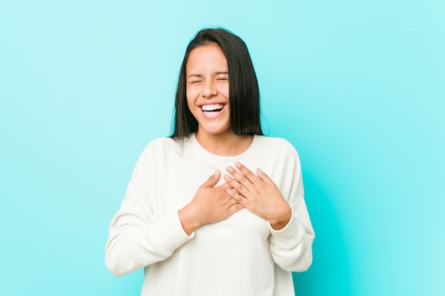 Giovane donna ispanica graziosa che ride tenendo le mani sul cuore, concetto di felicità.