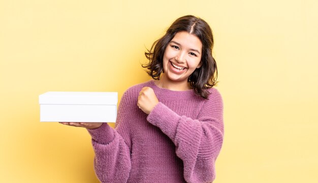 Giovane donna ispanica sentirsi felice e affrontare una sfida o festeggiare. concetto di scatola vuota