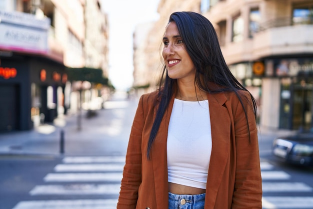 Giovane donna ispanica sorridente camminando fiducioso in strada