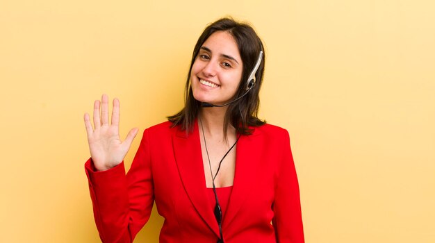 Giovane donna ispanica sorridente e dall'aspetto amichevole che mostra il concetto di telemarketing numero cinque