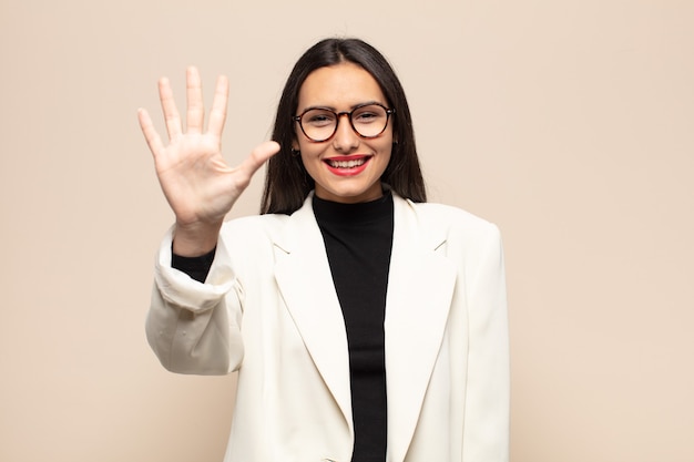 Giovane donna ispanica sorridente e dall'aspetto amichevole, mostrando il numero cinque o quinto con la mano in avanti, conto alla rovescia