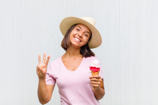 Giovane donna ispanica sorridente e dall'aspetto amichevole, mostrando il numero due o il secondo con la mano in avanti, il conto alla rovescia