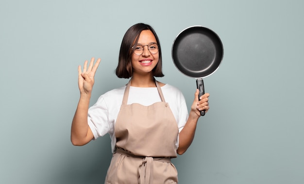 Giovane donna ispanica sorridente e dall'aspetto amichevole, mostrando il numero quattro o il quarto con la mano in avanti, conto alla rovescia