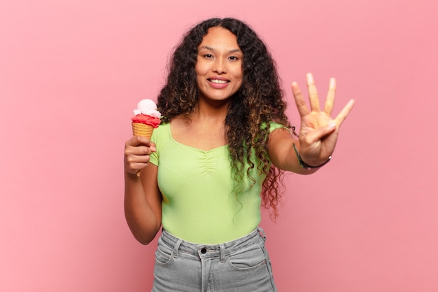 Giovane donna ispanica sorridente e dall'aspetto amichevole, mostrando il numero quattro o il quarto con la mano in avanti, conto alla rovescia