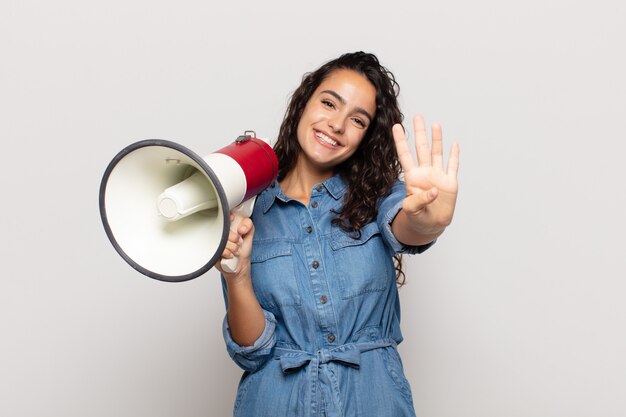 Giovane donna ispanica sorridente e dall'aspetto amichevole, mostrando il numero quattro o il quarto con la mano in avanti, il conto alla rovescia