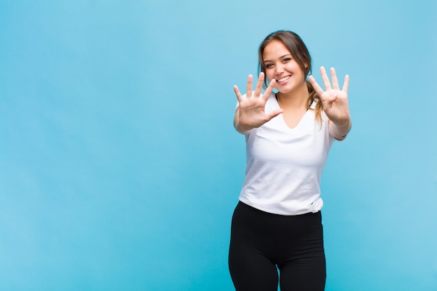 Giovane donna ispanica sorridente e guardando amichevole, mostrando il numero nove o nono con la mano in avanti, conto alla rovescia