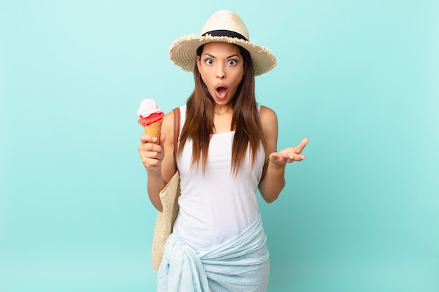 Giovane donna ispanica stupita, scioccata e stupita con un'incredibile sorpresa e con in mano un gelato. concetto estivo