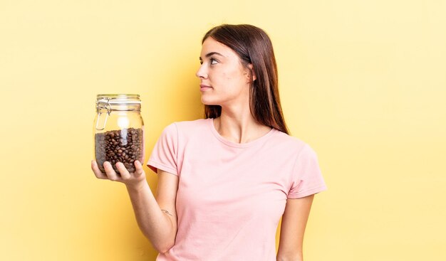 Giovane donna ispanica sulla vista di profilo pensando, immaginando o sognando ad occhi aperti. concetto di chicchi di caffè