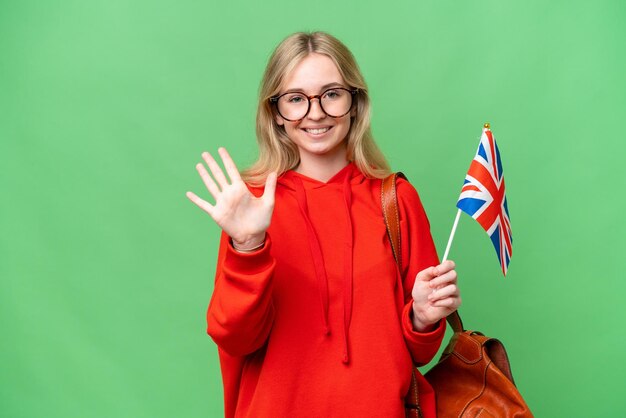Giovane donna ispanica tenendo una bandiera del Regno Unito su sfondo isolato contando cinque con le dita