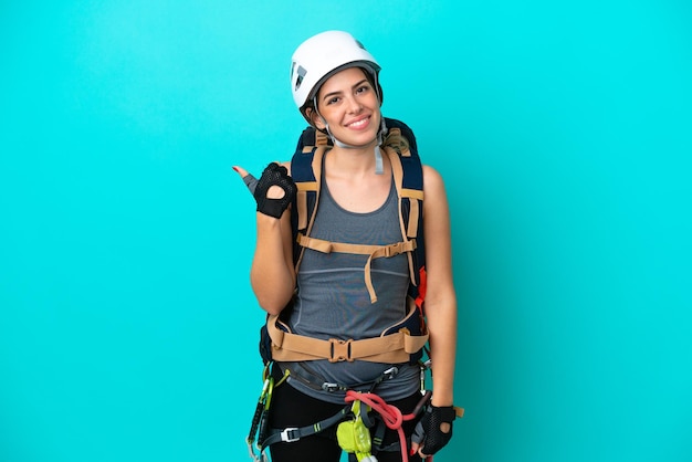 Giovane donna italiana rockclimber isolata su sfondo blu che punta di lato per presentare un prodotto