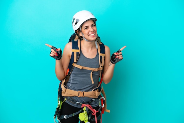 Giovane donna italiana rockclimber isolata su sfondo blu che punta il dito verso i laterali e felice
