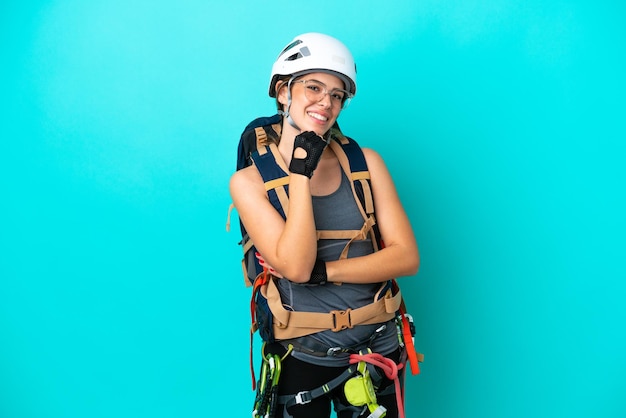 Giovane donna italiana rockclimber isolata su sfondo blu con occhiali e sorridente