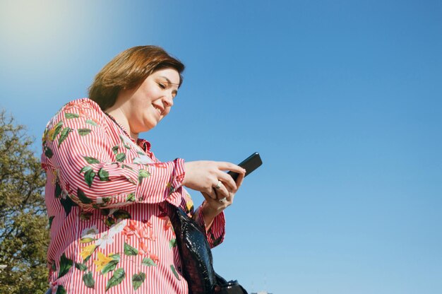 Giovane donna latina caucasica all'aperto sorridente mentre manda un sms al suo ragazzo al telefono
