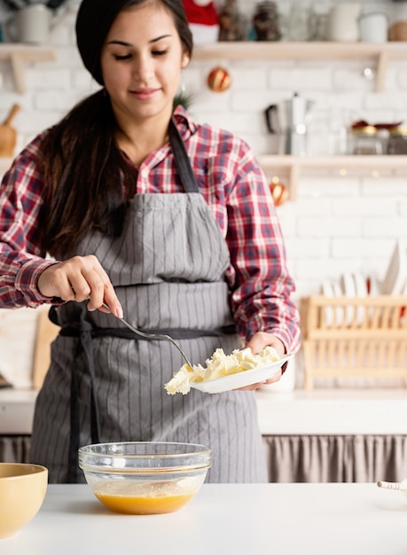 Giovane donna latina che aggiunge burro che cucina alla cucina